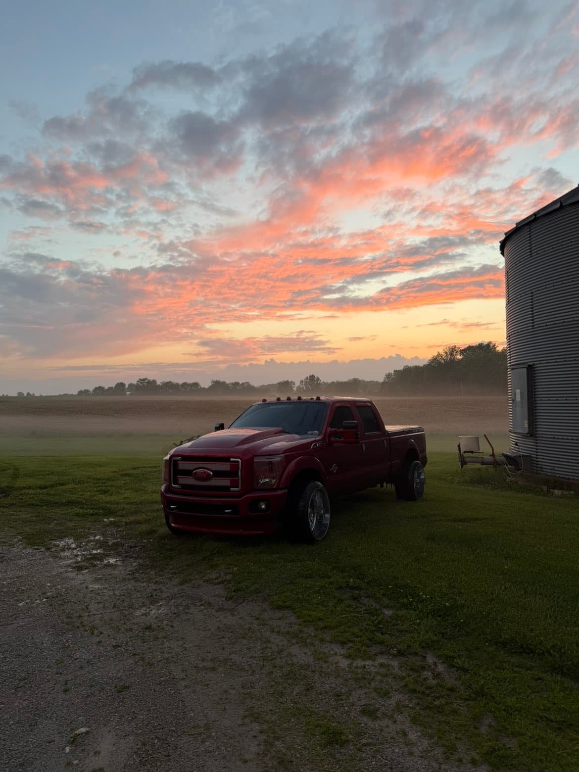 Custom red Ford Super Duty at grain silo at sunset — TP Customs LLC